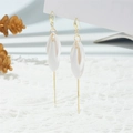 Close-up of elegant floral drop earrings with matte white petals and long gold tassels - White