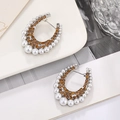 Macro shot of silver C-shaped earrings featuring amber rhinestones and white pearls - Silver Base Yellow Rhinestone