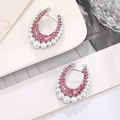 Macro detail of silver C-shaped earrings with pink zircons and white pearls on a tray - Silver / Pink