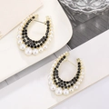 Macro shot of U-shaped earrings with black crystals and pearls on white ceramic - Gold Base Black Rhinestone