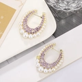 Detail of U-shape gold earrings with purple crystals and pearls on a white plate - Gold Base Purple Rhinestone