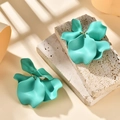Macro detail of mint green matte petal earrings on a textured stone surface with shadows - Lake Blue