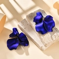 Close-up of matte deep blue petal earrings on a textured stone display with shadows - Pearlescent Royal Blue
