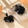 Detailed view of matte black floral petal earrings on stone with soft natural lighting - Black