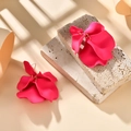 Macro shot of stylish matte rose pink petal earrings on a beige textured stone base - Rose Red