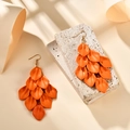 Detail of orange matte petal tassel earrings on a textured stone display stand - Orange Red (A1596)