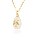 Macro view of gold egg pendant featuring a white floral pattern and crystal inlay - White