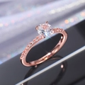 Vista macro di un anello in oro rosa con grande diamante solitario e pietre laterali - US 6 / Oro rosa