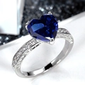 Vista macro dell'anello in argento con pietra a cuore blu intenso e pavé di diamanti laterali - US 6 / Blu