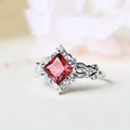 Detailed close-up of a silver ring featuring a red square gem and zircon accents - Red