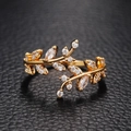 Detailaufnahme eines goldenen Blatt-Ringes mit funkelnden Zirkoniasteinen auf Leder - Einstellbar Offen / Gold