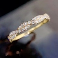 Makro-Detail des goldenen gedrehten Ringes mit Pavé-Kristallen auf dunklem Grund - US 7 / Gold