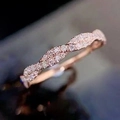 Makroaufnahme von roségoldenem Ring mit gedrehtem Band und weißem Zirkonia-Besatz - US 7 / Roségold