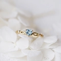 Elegante anello con gemma blu a cuore, fascia dorata intrecciata e piccoli diamanti - US 6 / Oro Blu Zirconia