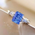 Vista macro del anillo con piedra azul talla radiant y piedras laterales en plata - US 5 / Azul