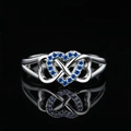 Silver infinity heart ring with blue zircon stones on a reflective black background - US 5 / Blue