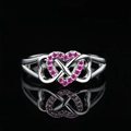 Infinity heart ring with pink pavé gemstones in silver finish against a dark reflection - US 5 / Red