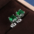 Macro detail of emerald green square-cut zircon earrings with silver four-claw setting - Green