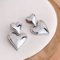 Polished silver layered heart stud earrings displayed on a minimalist white ceramic tray - Steel
