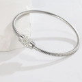 Close-up of silver snake chain bracelet featuring a round clasp pave-set with white crystals - Silver