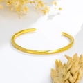 Vue détaillée d'un jonc ouvert en spirale or rose poli avec des fleurs jaunes sèches - Or Femme