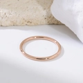Gros plan d'une bague minimaliste en or rose de 1,5 mm sur un support en pierre blanche - US 5 / Or rose