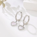 Detailed macro shot of silver hoop earrings with a pink mother-of-pearl heart and pavé stones - White-Steel