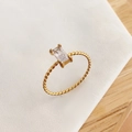 Dettaglio anello a treccia dorato con zircone rettangolare incastonato a quattro griffe - US 7 / Oro-Zircone Bianco