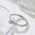 Macro shot of silver titanium steel ring featuring a bezel-set round sparkling zircon - US 5 / Steel