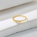 Macro view of minimalist gold four-prong ring with a round clear zircon stone - US 5 / Gold