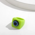 Macro detail of fluorescent green resin square ring featuring 3D blue evil eye element - Fixed Size / Green