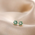 Macro shot of gold flower earrings with green gemstone petals and central diamond - Green Rhinestone