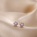 Detailed macro view of small flower stud earrings with purple crystals and gold base - Purple Crystal Flower