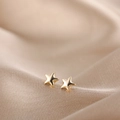Detailed macro view of golden star stud earrings on elegant champagne silk fabric background - Gold Five-pointed Star