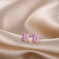 Macro shot of purple butterfly earrings with gold plating on premium silk fabric - Pink Butterfly