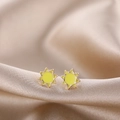 Macro shot of sun-shaped golden earrings with yellow enamel on silk fabric surface - Yellow Sunflower