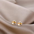 Detail view of gold screw head earrings with orange enamel on luxury champagne silk - Gold Screw