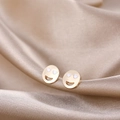 Close-up of Y2K gold smile face stud earrings with white heart eyes on silk fabric - Gold Smiley Face