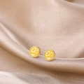 Macro shot of yellow enamel smiley face stud earrings on soft champagne silk fabric - Yellow Smiley Face