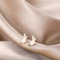 Macro shot of gold-plated rabbit stud earrings with crystal eyes on silk fabric - Gold Rabbit