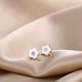 Macro shot of white enamel daisy earrings with gold edges and central zircon stone - White Flower