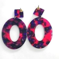 Dettaglio di orecchini ovali in acrilico con texture marmorizzata rosa e viola vivace - Rosa Viola Nero