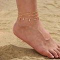 Detailansicht von mehrlagigen 14K Gold-Fußkettchen mit Zirkonia auf einem Strandhintergrund - Zirkon Anhänger Stil (JL0033)