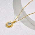 Close-up of gold titanium necklace with oval faceted crystal pendant on white stand - Gold-White Zirconia