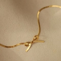 Macro detail of 18K gold stainless steel bow necklace with flat snake chain texture - Necklace / Gold