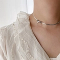 Detail of silver bow pendant on a polished snake chain choker worn with white lace top - Necklace / Steel