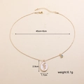 Dettaglio del ciondolo ovale dorato con motivo floreale e gemma blu su collana a catena - poinsettia