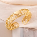 Polished gold multi-layer spiral cuff bracelet with central heart charm on silk background - Gold