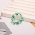 Primer plano detallado de un anillo de resina transparente con un diseño de cara sonriente - Verde