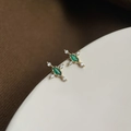 Detailaufnahme goldener Sternenohrringe mit Smaragd-Edelstein und weißen Zirkoniasteinen - Mini-Kreuz Zirkonia (Silberstift)
